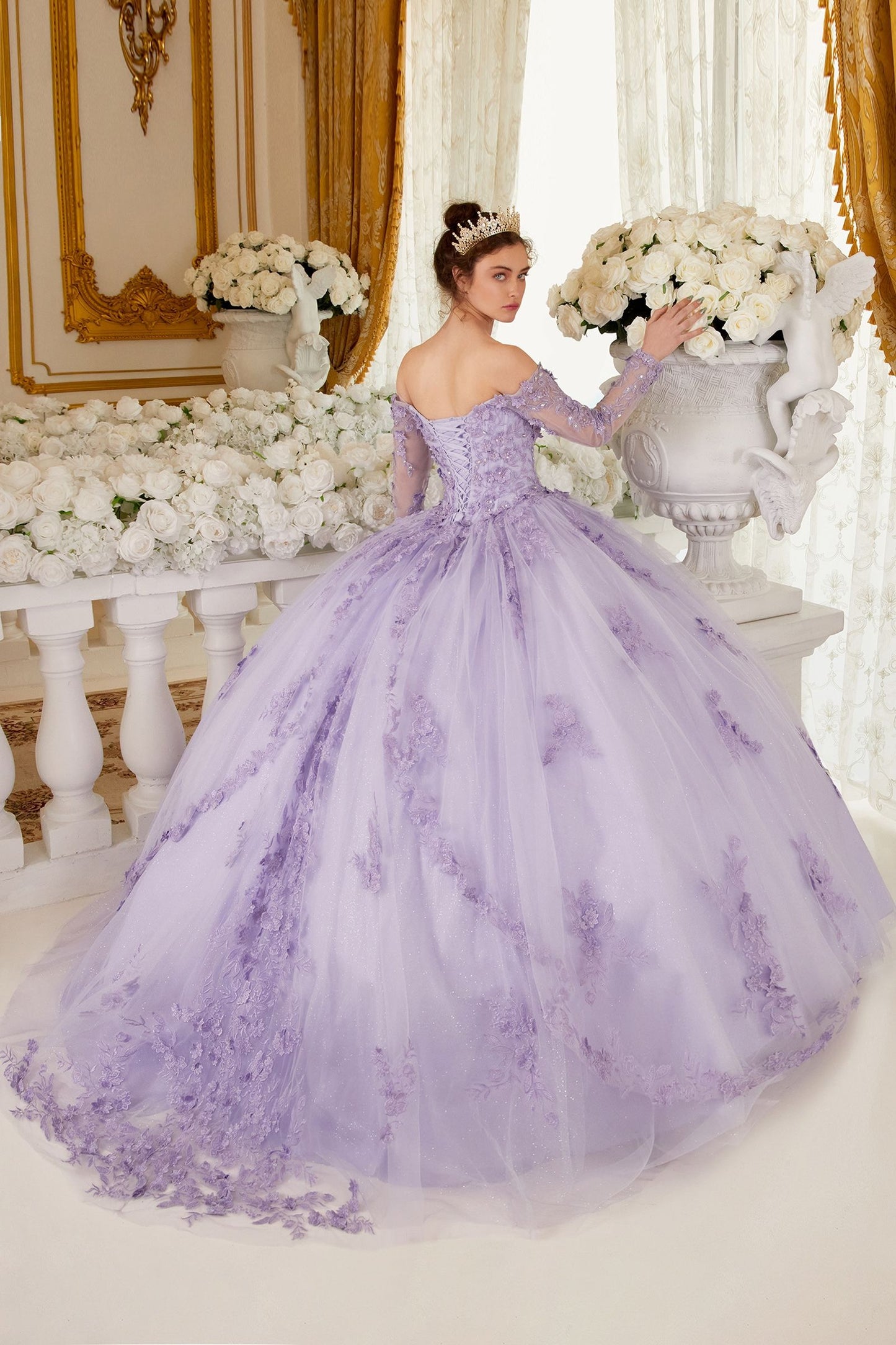 This gorgeous lilac off-the-shoulder, long-sleeved ball gown is an enchanting piece of work that will make you look like a quinceanera princess! The crafted lace and beaded applique add the perfect amount of shine to the bodice. Adding to the charm of this dress are the dimensional floral appliques giving it a unique and creative flair