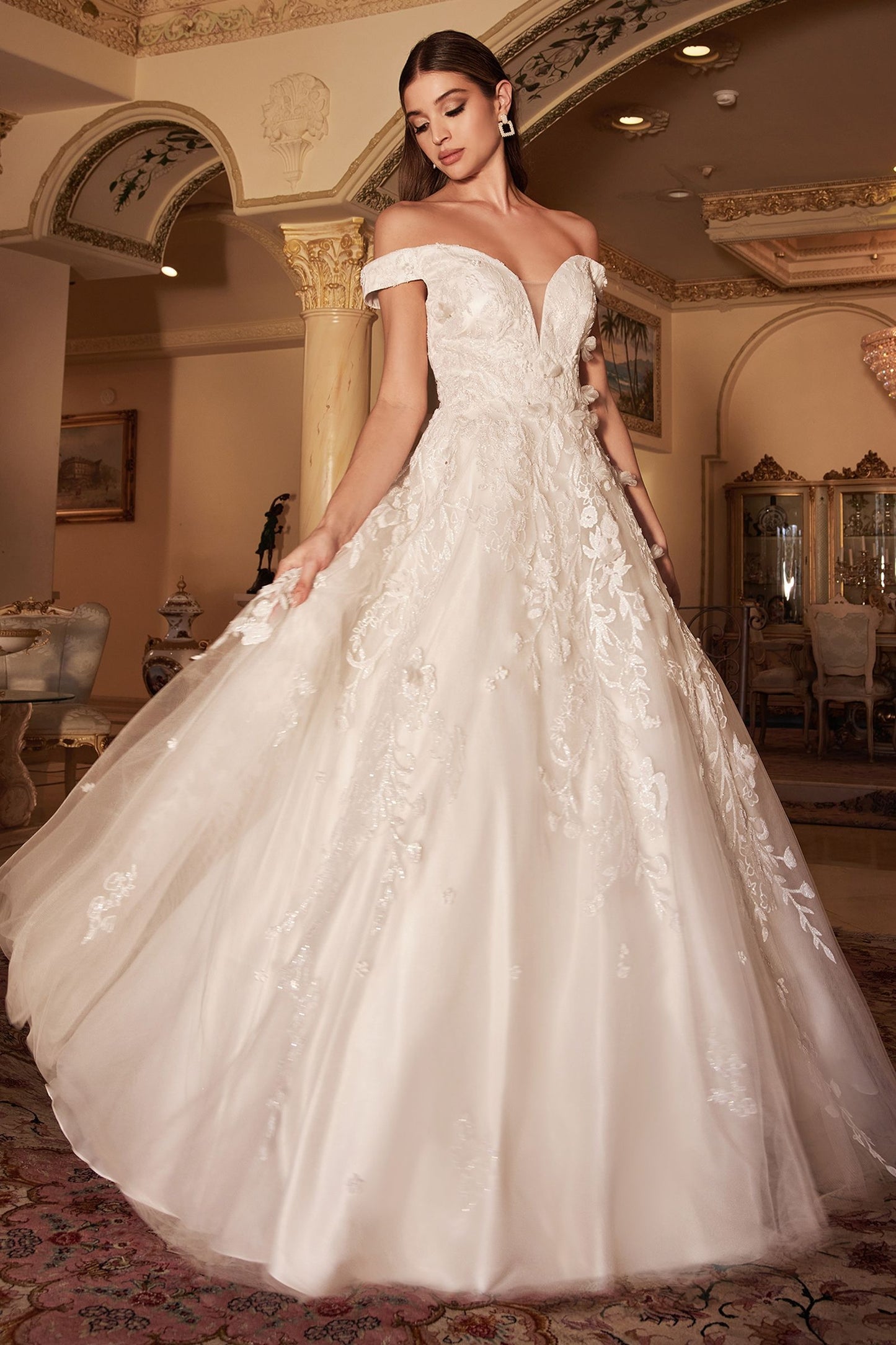 Peony White Gown is a layered tulle ball gown with floral diamond glitter motif trickling down the gown. 3D organza flowers add couture depth to the garment, while the off-white tone of the dress softly blends into the shimmering embellishment. The bodice features a off shoulder bodice that is fully lined mid back for bra coverage. The skirt is A-line shape with crinoline to support the silhouette.