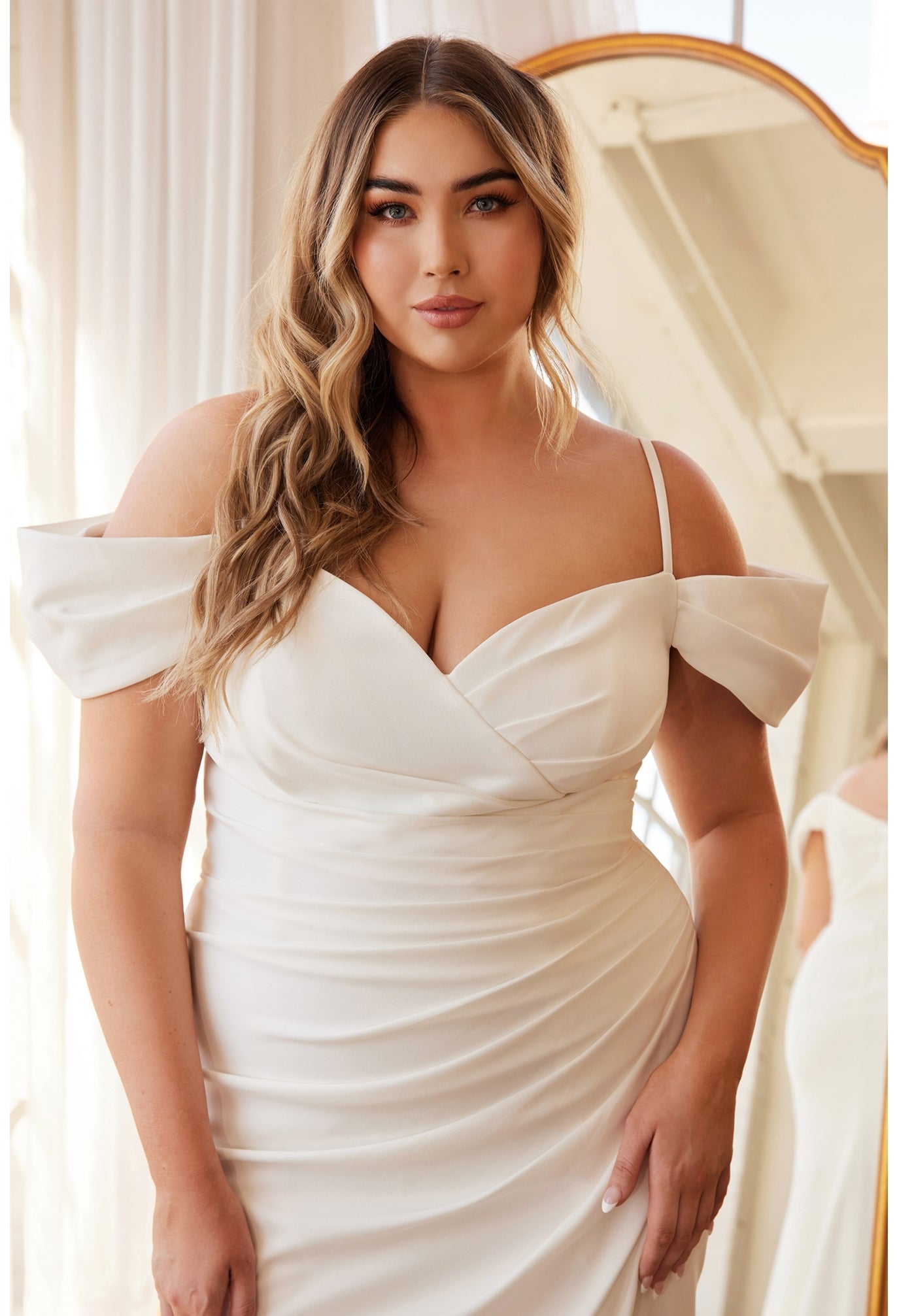 Designed for a more modern bride or small intimate wedding this sophisticated gown is perfection. The off the shoulder pleated sleeve drapes around the shoulders while a thin strap holds the gown. A sweetheart neckline pleats into the side seam for a flattering fit opening up to a subtle leg slit