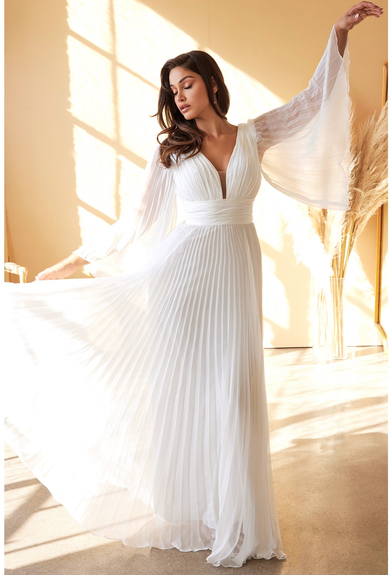 An elegant and sophisticated option for a boho wedding or destination elopement. This chiffon gown is pleated from sleeve to hem and gathered at the deep v-neckline and waist. An open mid back has a center back zipper closure.