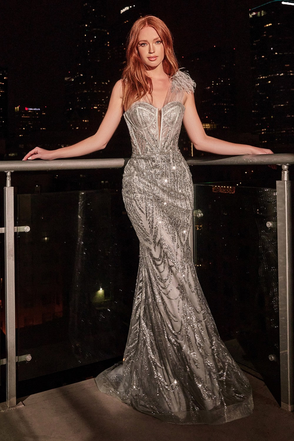 Equally regal and glamorous, this statement piece has a glitter lace pattern outlining and contouring the fitted figure. The structured bodice has a bust cup outline and sheer illusion tulle wrapping around the chest and onto delicate straps topped with a dainty feather detail.