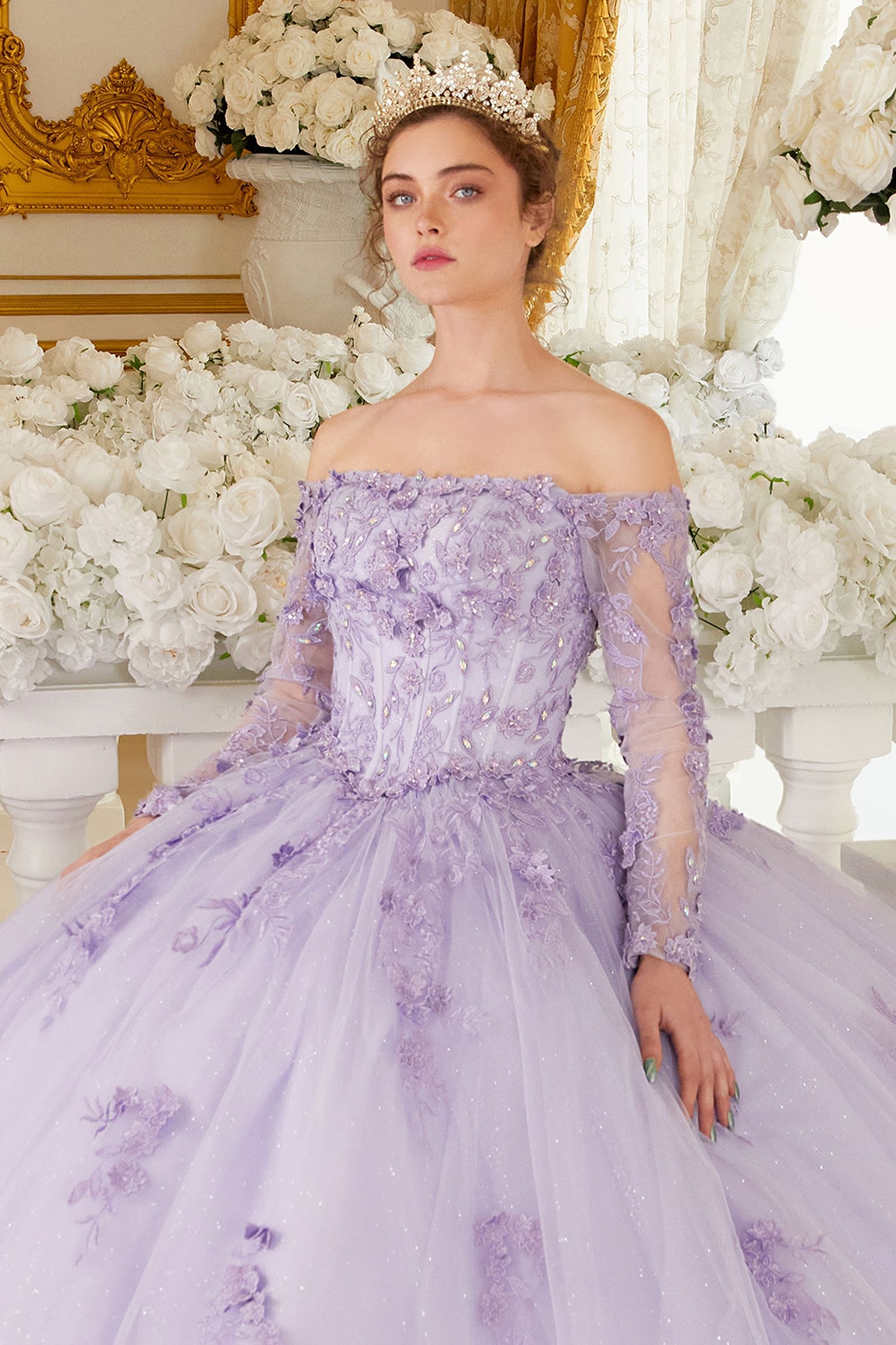 This gorgeous lilac off-the-shoulder, long-sleeved ball gown is an enchanting piece of work that will make you look like a quinceanera princess! The crafted lace and beaded applique add the perfect amount of shine to the bodice. Adding to the charm of this dress are the dimensional floral appliques giving it a unique and creative flair